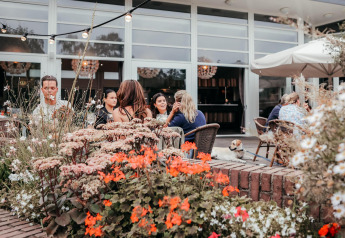 Udendørs spiseområde ved Waterlodge i Recreatiepark De Achterste Hoef, Holland, omgivet af blomster.