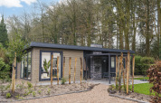 Moderne lodge ved Zypendaal Comfort i Veluwepark de Bosgraaf, Holland, omgivet af træer og natur.