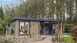 Moderne lodge ved Zypendaal Comfort i Veluwepark de Bosgraaf, Holland, omgivet af træer og natur.