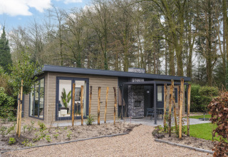 Moderne lodge ved Zypendaal Comfort i Veluwepark de Bosgraaf, Holland, omgivet af træer og natur.