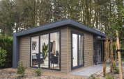 Moderne lodge ved navn Zypendaal Comfort i Veluwepark de Bosgraaf, Holland, omgivet af grøn natur.