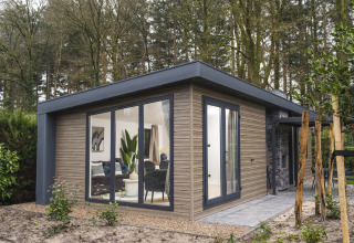 Moderne lodge ved navn Zypendaal Comfort i Veluwepark de Bosgraaf, Holland, omgivet af grøn natur.
