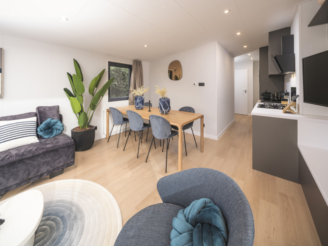 Helles, modernes Wohnzimmer in der Zypendaal Comfort-Lodge mit Essbereich im Veluwepark de Bosgraaf, Niederlande.