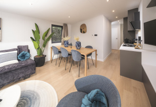 Lyst og moderne opholdsområde i Zypendaal Comfort-lodgen med spisebord og stilfuld indretning i Holland.