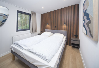 Moderne soveværelse på Zypendaal Comfort i Veluwepark de Bosgraaf i Holland med træpanelvæg og kunst.