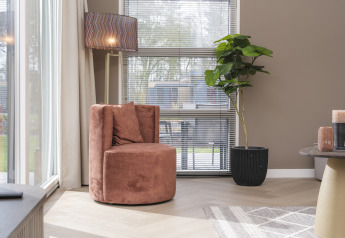 Stilfuldt hjørne med rund stol, gulvlampe og grøn plante i Batenburgh Deluxe-lodge, Veluwepark de Bosgraaf.
