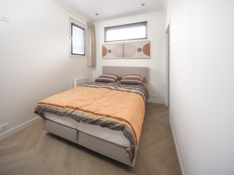 Camera moderna al Batenburgh Deluxe nel Veluwepark de Bosgraaf, Paesi Bassi, con letto matrimoniale e arte.