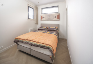 Moderne slaapkamer in Batenburgh Deluxe op Veluwepark de Bosgraaf, Nederland, met tweepersoonsbed en kunst.