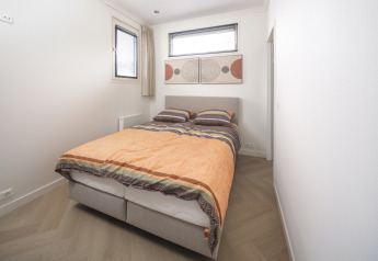 Camera moderna al Batenburgh Deluxe nel Veluwepark de Bosgraaf, Paesi Bassi, con letto matrimoniale e arte.