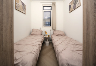 Cozy bedroom with two single beds, modern art, and a window at Batenburgh Deluxe, Veluwepark de Bosgraaf, Netherlands.