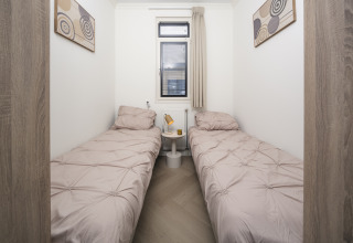 Cozy bedroom with two single beds, modern art, and a window at Batenburgh Deluxe, Veluwepark de Bosgraaf, Netherlands.