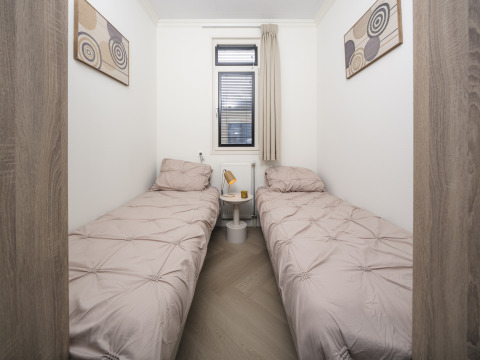 Gemütliches Schlafzimmer mit zwei Einzelbetten, Kunstwerken und Fenster im Batenburgh Deluxe, Veluwepark de Bosgraaf.