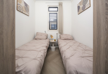 Gemütliches Schlafzimmer mit zwei Einzelbetten, Kunstwerken und Fenster im Batenburgh Deluxe, Veluwepark de Bosgraaf.