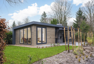 Lodge moderno Zypendaal en Veluwepark de Bosgraaf, Países Bajos, con jardín y grandes ventanales.