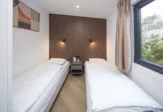 Habitación moderna en la cabaña Zypendaal de Veluwepark de Bosgraaf, Países Bajos, con dos camas individuales y ventana.