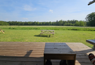 Zicht vanaf een houten terras op grasvelden en banken in vakantiepark Mooirust, Utrecht, Nederland.