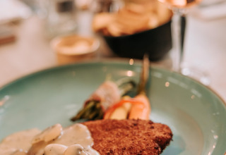 Paneret schnitzel med svampesovs, serveret med grøntsager, på en blå tallerken på restaurant i De Achterste Hoef.