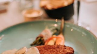 Escalope empanado con salsa de champiñones y verduras, servido en un plato azul en De Achterste Hoef.