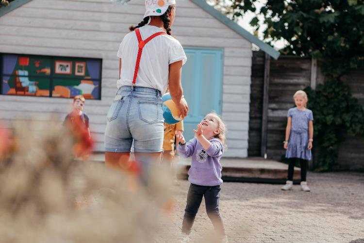 Kinderen spelen buiten met een volwassene bij een vakantiehuis op Recreatiepark De Achterste Hoef, Nederland.