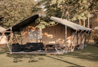 Glamping-telt med terrasse og havemøbler i solrigt område på Recreatiepark De Achterste Hoef, Holland.