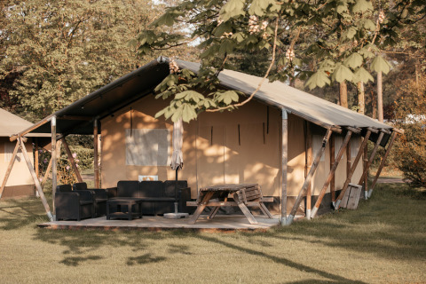 Glamping tent with porch, seating area and picnic table at Recreatiepark De Achterste Hoef, Netherlands.