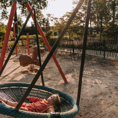 Niño con chupete relajándose en un columpio redondo en el parque infantil de De Achterste Hoef, Países Bajos.