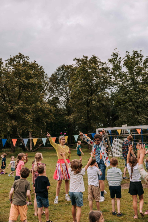Kinder spielen draußen mit Erwachsenen in bunter Kleidung während einer Feier im Noord-Brabant, Niederlande.