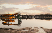 Uno scivolo d'acqua giallo riflesso nel lago calmo al Recreatiepark De Achterste Hoef durante il tramonto.