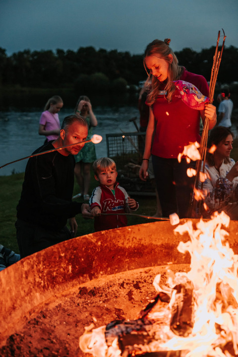 Gezin roostert marshmallows bij het kampvuur in Recreatiepark De Achterste Hoef, Nederland, bij zonsondergang.