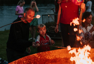 Family roasting marshmallows by a campfire at Recreatiepark De Achterste Hoef, North-Brabant, Netherlands.