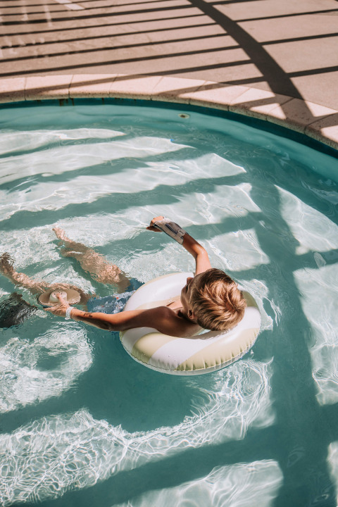 Niño relajándose en un flotador inflable en la piscina de Recreatiepark De Achterste Hoef, Países Bajos.