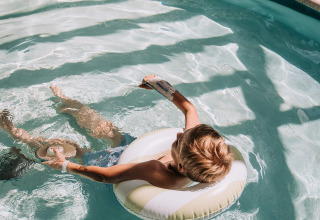 Dreng slapper af i oppustelig badering i swimmingpoolen på Recreatiepark De Achterste Hoef, Holland.