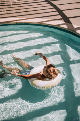 Jongen ontspant op opblaasbare zwemband in het zwembad van Recreatiepark De Achterste Hoef, Nederland.