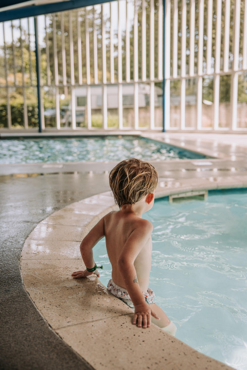Un bambino siede sul bordo di una piscina coperta al Recreatiepark De Achterste Hoef nei Paesi Bassi.