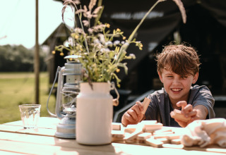 Dreng leger med træklodser ved et bord i solskin ved Feather Down Botterheerd, Groningen, Holland.