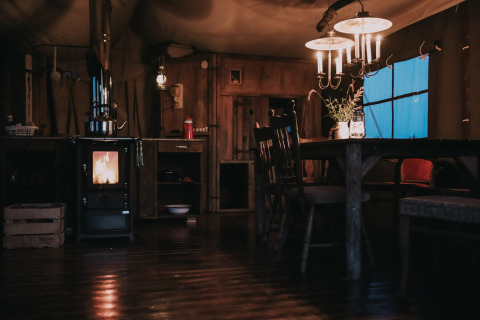Acogedor interior rústico con estufa de leña y mesa de comedor en Feather Down Botterheerd, Groningen, Países Bajos.