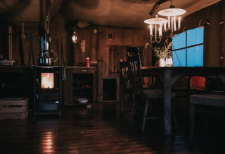Sfeervol, rustiek interieur met houtkachel en eettafel bij Feather Down Botterheerd, Groningen, Nederland.