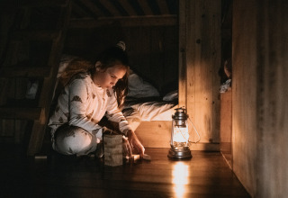 Bambina gioca con blocchi di legno vicino a una lanterna in una baita al Feather Down Botterheerd, Groningen.