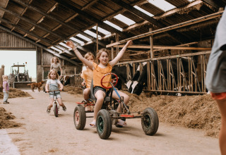 Bambini giocano e pedalano in una stalla presso Feather Down Botterheerd, parco vacanze a Groningen, Paesi Bassi.