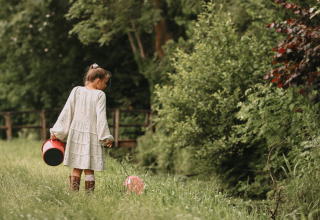 Bambina con secchio e palloncino in un campo verde a Feather Down Botterheerd, Groningen, Paesi Bassi