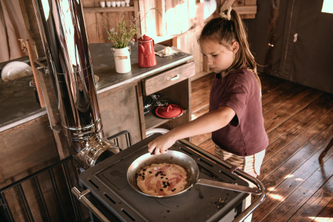 Un bambino cucina su una stufa in una baita rustica al parco vacanze Feather Down Botterheerd a Groningen, Paesi Bassi.