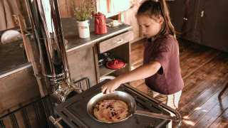 Un niño cocina en una cabaña rústica en Feather Down Botterheerd, un parque vacacional en Groningen, Países Bajos.