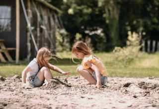 Due bambine giocano nella sabbia al parco vacanze Feather Down Botterheerd a Groningen, Paesi Bassi.