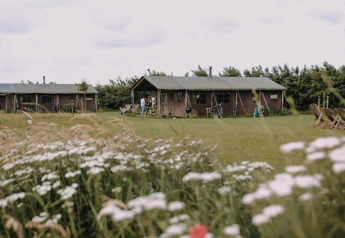 Safari-telt med privat bruser ved Feather Down Boerderij Ameland, omgivet af blomster og natur.