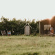 Safari teltet Tent house med privat udendørs bruser, solnedgang, grøn eng og afslappede besøgende.