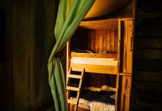 Wooden bunk beds and curtain in a safari tent named Tent house with a private shower next door.
