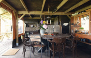 Interior de alojamiento glamping con mesa de madera, sillas diferentes y una cocina abierta acogedora.