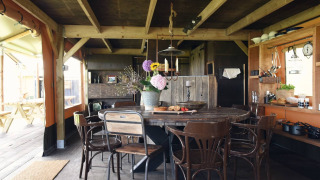 Innenraum einer Glamping-Unterkunft mit rustikalem Esstisch, Holzbalken und gemütlicher Küche.