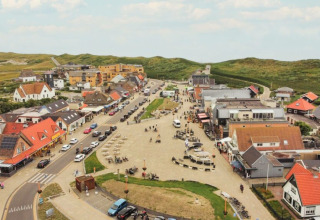Luchtfoto van een glamping-accommodatie met kleurrijke daken, gezellige sfeer en groene heuvels.