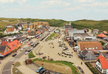 Aerial view of a glamping site with colorful roofs, cozy accommodations, and green hills in the background.